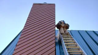 Construction Jobs in Logan CCX Construction worker in Logan working on a roof with a chimney.